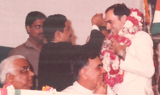 Prime Minister Rajiv Gandhi being garlanded on stage